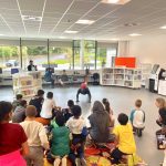 A group of children watch someone do football tricks in a library.