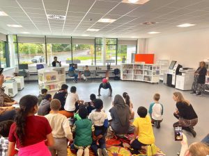 A group of children watch someone do football tricks in a library.